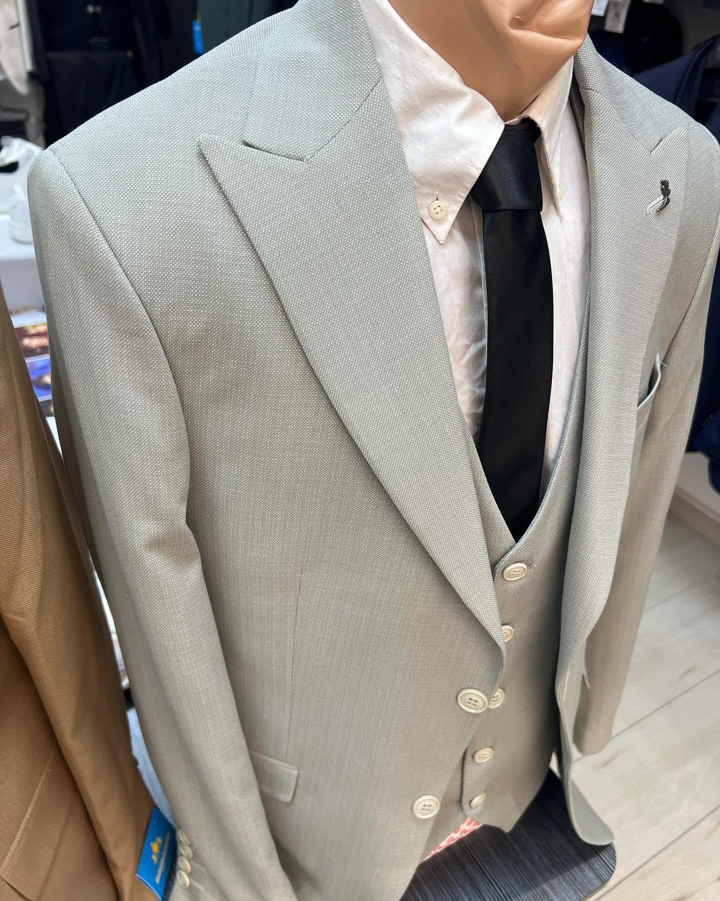 Close-up of a light gray three-piece suit on a mannequin, framed from the shoulders to the waist under indoor lighting.